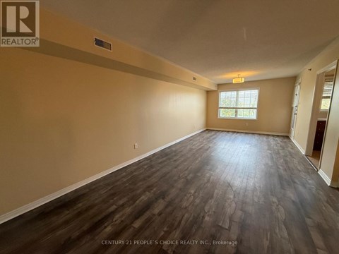 A spacious room with wooden flooring and a window.