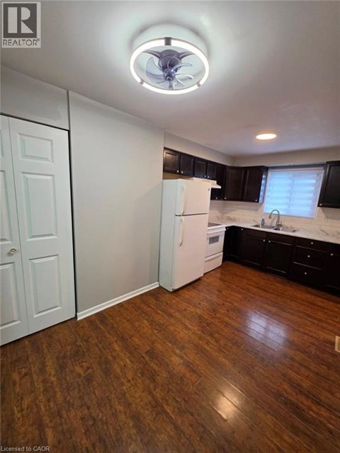 A kitchen with a white fridge and wooden floors.
