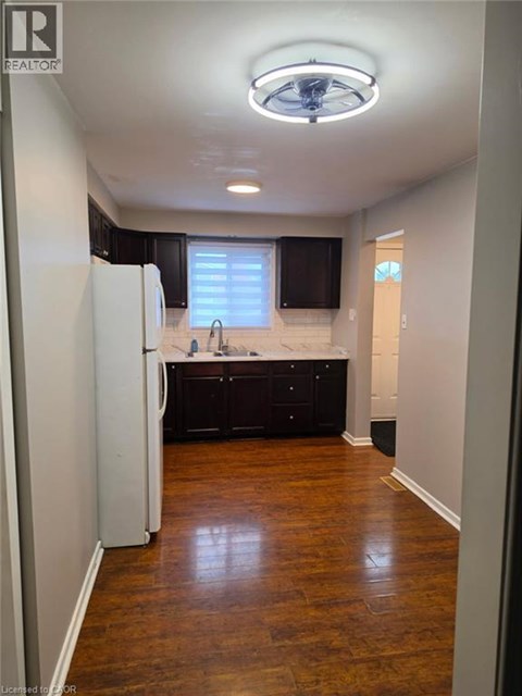 A kitchen with dark wood floors and white appliances.