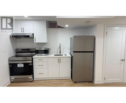 A kitchen with white cabinets and a stainless steel refrigerator.