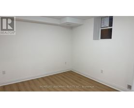 A room with white walls and wooden flooring, with a window on the right wall.