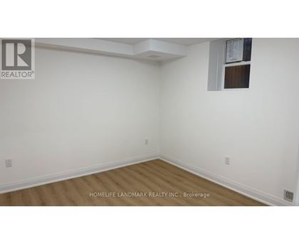 A room with white walls and wooden flooring, with a window on the right wall.
