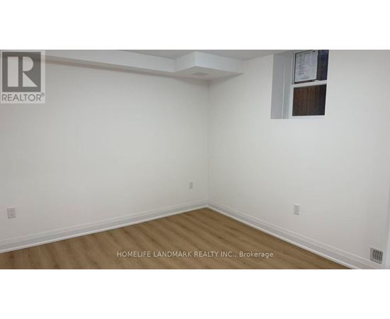 A room with white walls and wooden flooring, with a window on the right wall.
