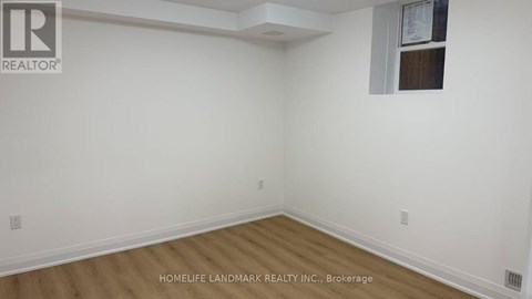 A room with white walls and wooden flooring, with a window on the right wall.