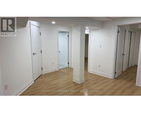 A white hallway with doors on both sides and a brokerage logo in the top left corner.