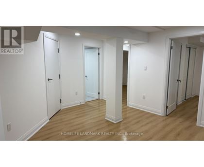A white hallway with doors on both sides and a brokerage logo in the top left corner.