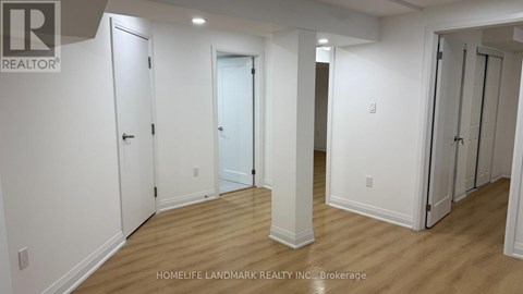 A white hallway with doors on both sides and a brokerage logo in the top left corner.