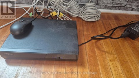 A black computer mouse is placed on a black box with a power cord plugged into an outlet.