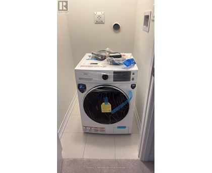A white dryer with a yellow tag on the door sits in a small room.