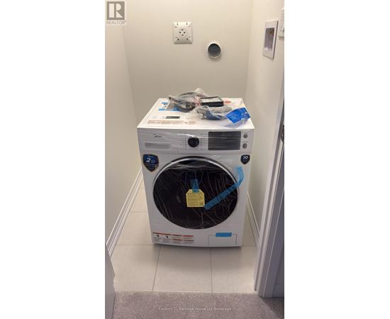 A white dryer with a yellow tag on the door sits in a small room.