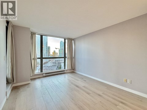 A spacious room with a large window overlooking a cityscape.