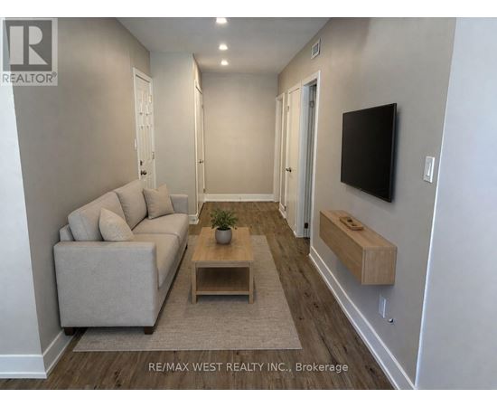 A living room with a couch, a coffee table, and a flat screen TV mounted on the wall.