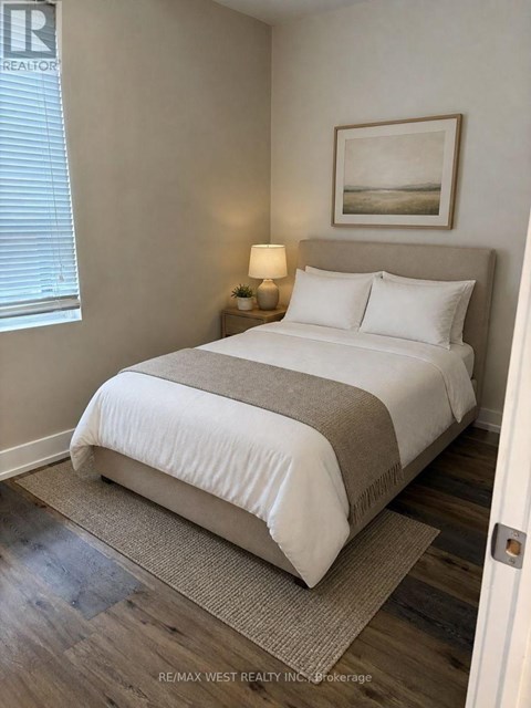 A bedroom with a large bed and a nightstand with a lamp.