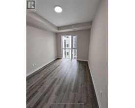 A room with wooden flooring and a doorway leading to another room.