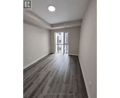A room with wooden flooring and a doorway leading to another room.