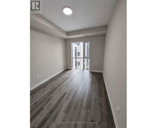 A room with wooden flooring and a doorway leading to another room.