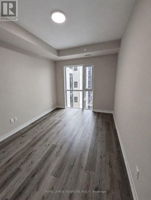 A room with wooden flooring and a doorway leading to another room.