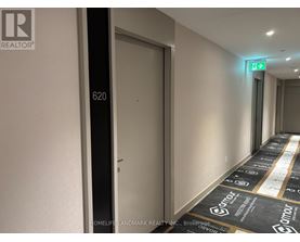 A hallway with a green exit sign and a door with the number 620 on it.