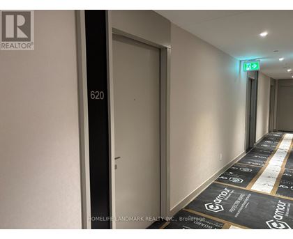 A hallway with a green exit sign and a door with the number 620 on it.