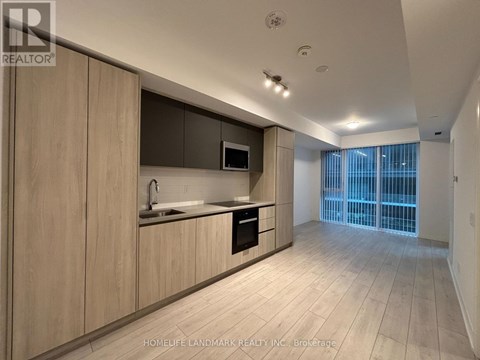 A modern kitchen with wooden cabinets and a microwave above the stove.