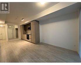 A spacious room with wooden flooring and a built-in cabinet with a microwave and oven.