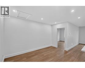A spacious room with wooden flooring and white walls.