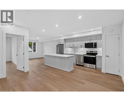 A modern kitchen with white cabinets and a wooden floor.