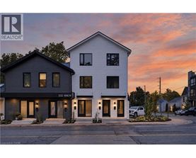 A modern two-story house with a realtor logo on the top left corner.