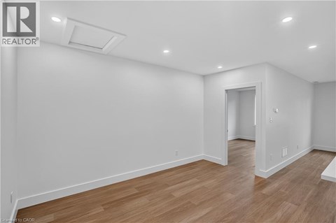 A spacious room with wooden flooring and white walls.
