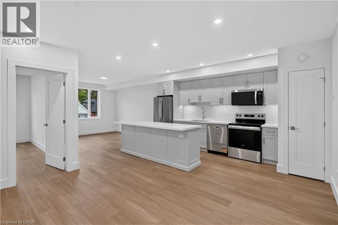 A modern kitchen with white cabinets and a wooden floor.