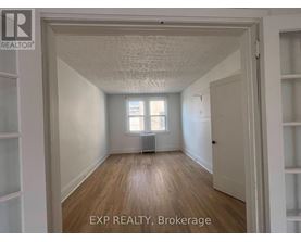 A room with wooden floors and white walls, with a window and a radiator.