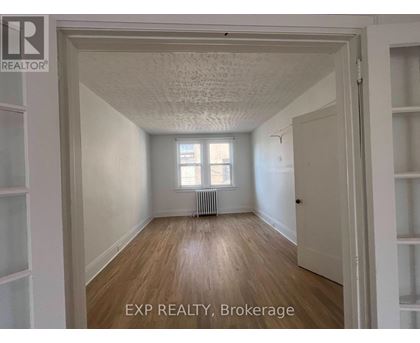 A room with wooden floors and white walls, with a window and a radiator.