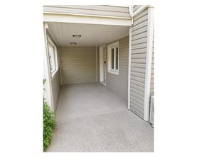 A small, white, enclosed porch with a grey carpet.