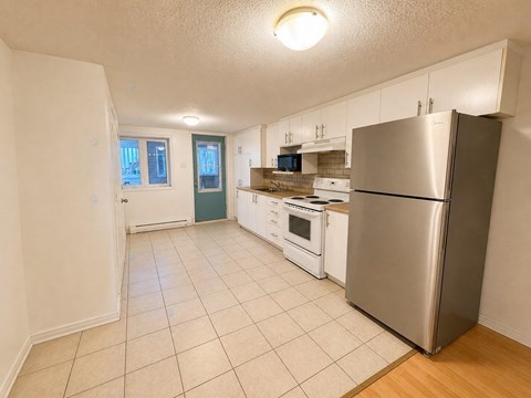 A kitchen with a refrigerator, oven, and microwave.