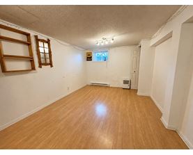 A room with wooden flooring and a window with blinds.