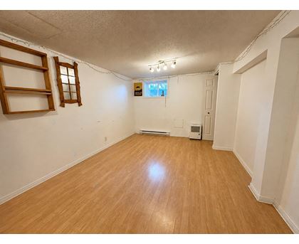 A room with wooden flooring and a window with blinds.