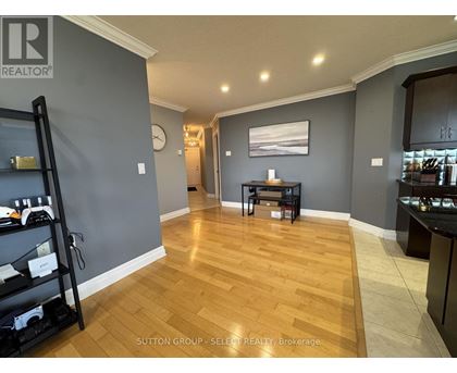 A room with wooden flooring and a grey wall with a clock on it.