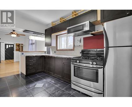 A modern kitchen with a stainless steel oven and black cabinets.