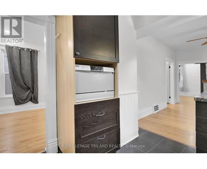 A kitchen with a wooden floor and a white wall.