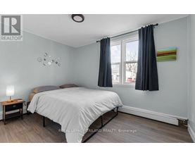 A bedroom with a bed, nightstand, and window.