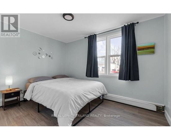 A bedroom with a bed, nightstand, and window.