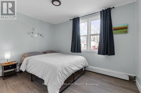 A bedroom with a bed, nightstand, and window.