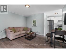 A living room with a couch, coffee table, and a dining area in the background.