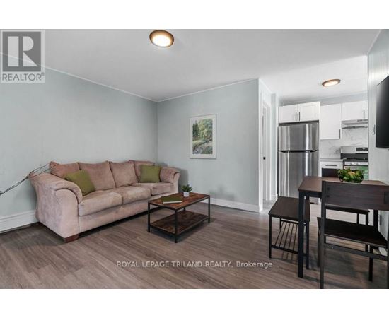 A living room with a couch, coffee table, and a dining area in the background.