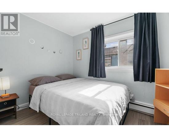 A bedroom with a bed, nightstand, and window with curtains.