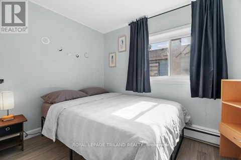 A bedroom with a bed, nightstand, and window with curtains.