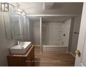 A bathroom with a sink, mirror, and bathtub.