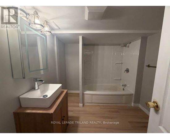 A bathroom with a sink, mirror, and bathtub.