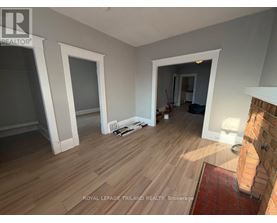 A room with wooden flooring and white walls, with a brick column on the right side.