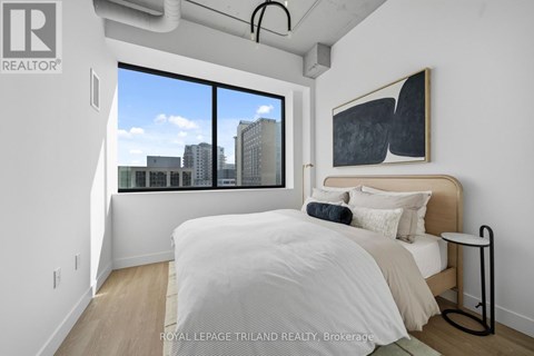 A bedroom with a large bed and a city view through the window.
